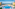 Luxury hotel resort pool with fountain, palm trees, ocean view, and sun loungers.