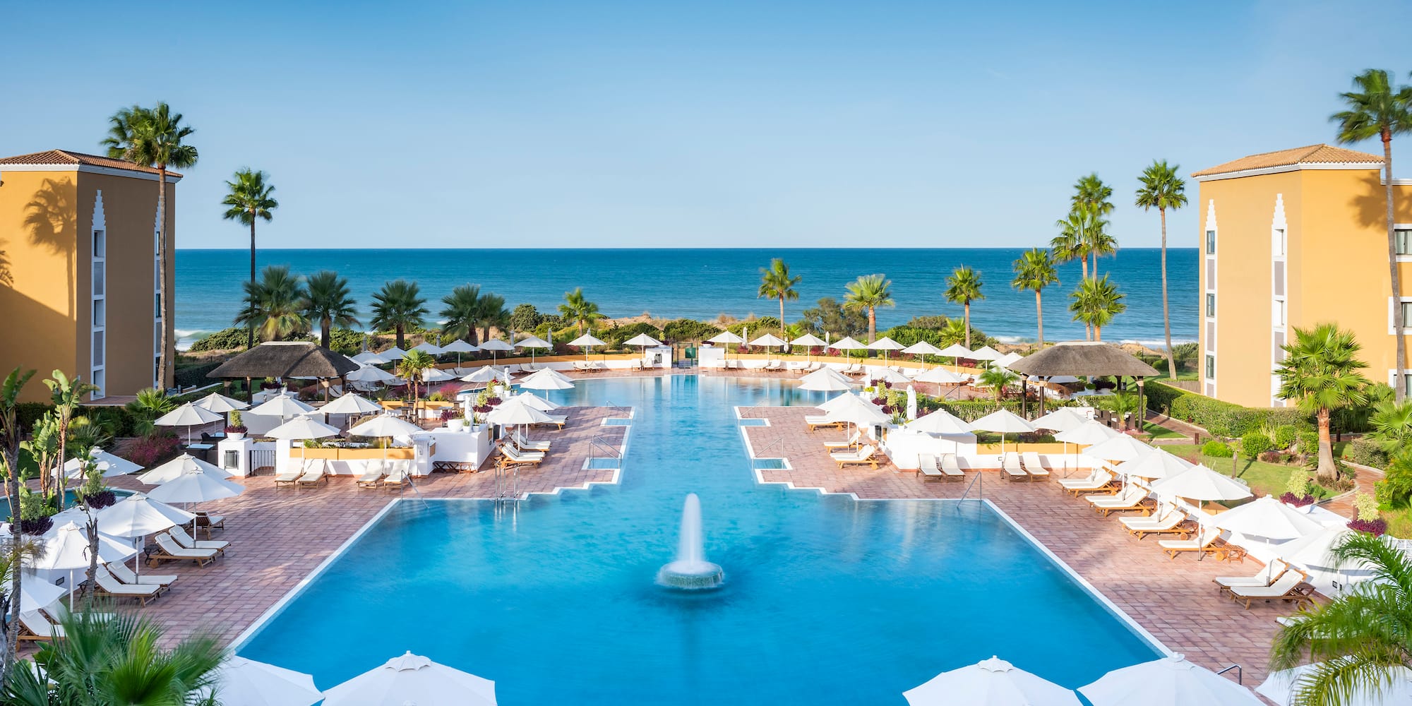 a pool with umbrellas and chairs and a fountain in the middle
