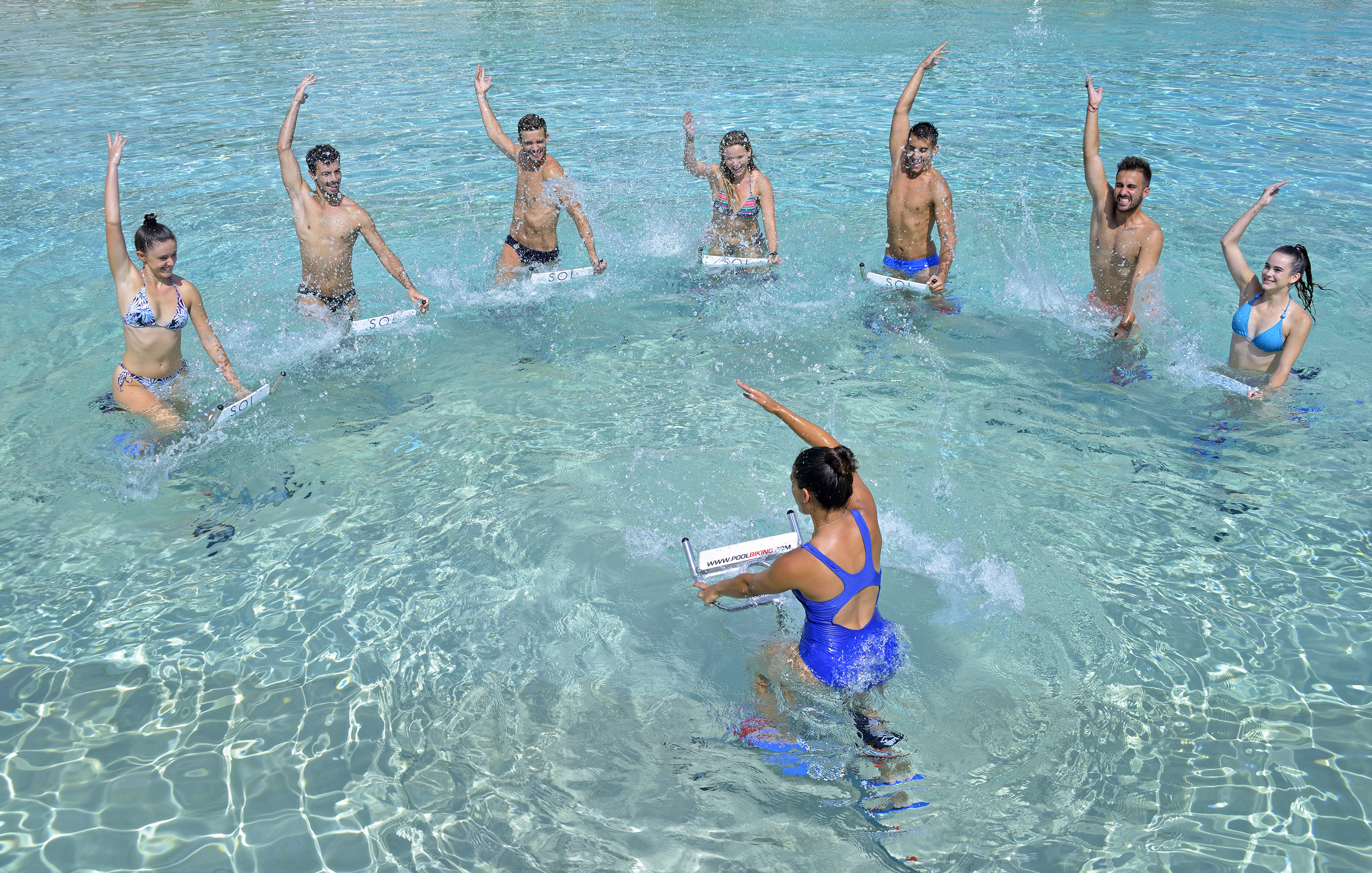 Happy group enjoying aqua cycling workout in clear blue pool.