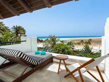 a deck with chairs and a beach view