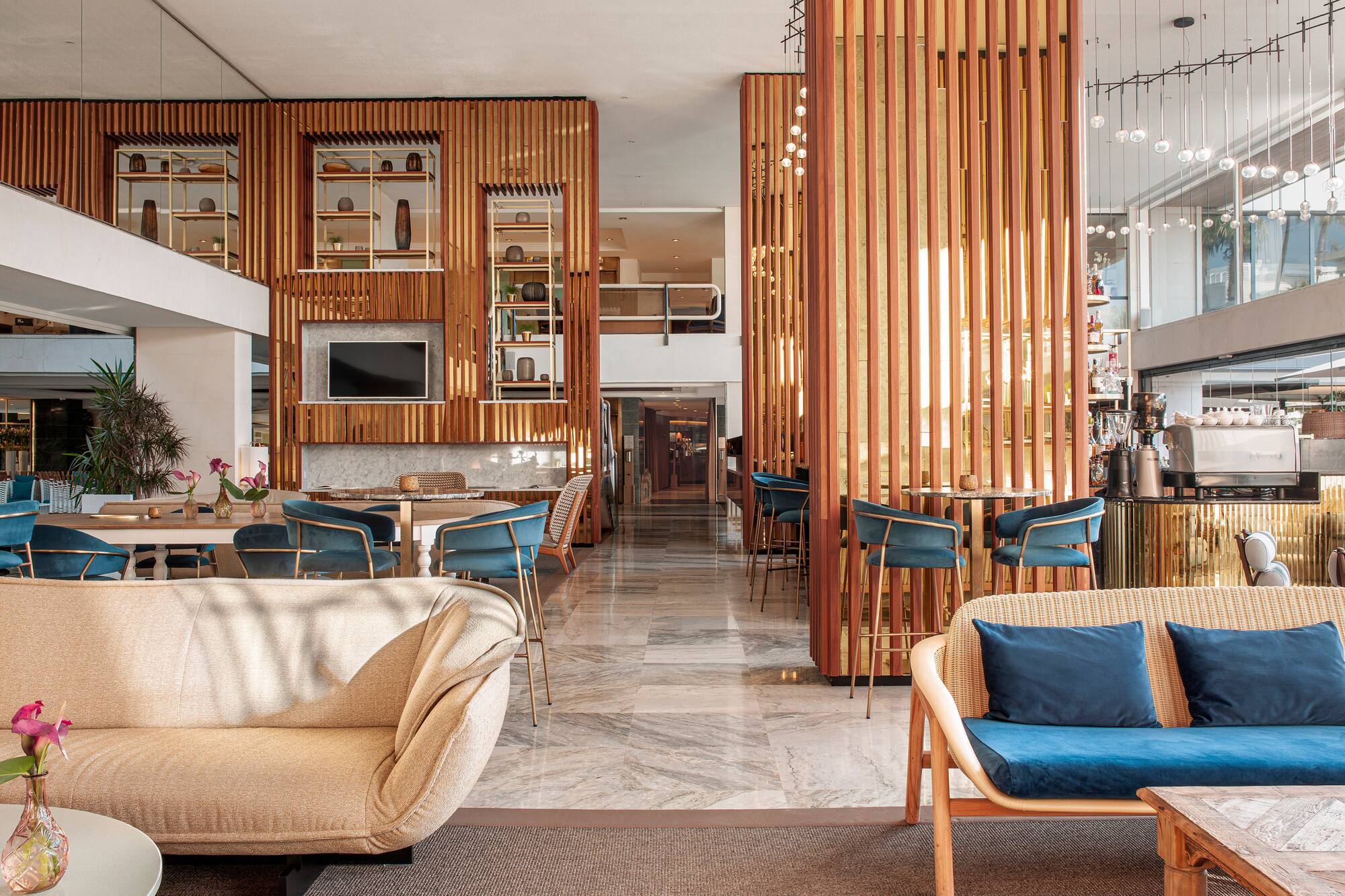 Modern hotel interior with wooden screens, stylish seating, marble floor, bar.