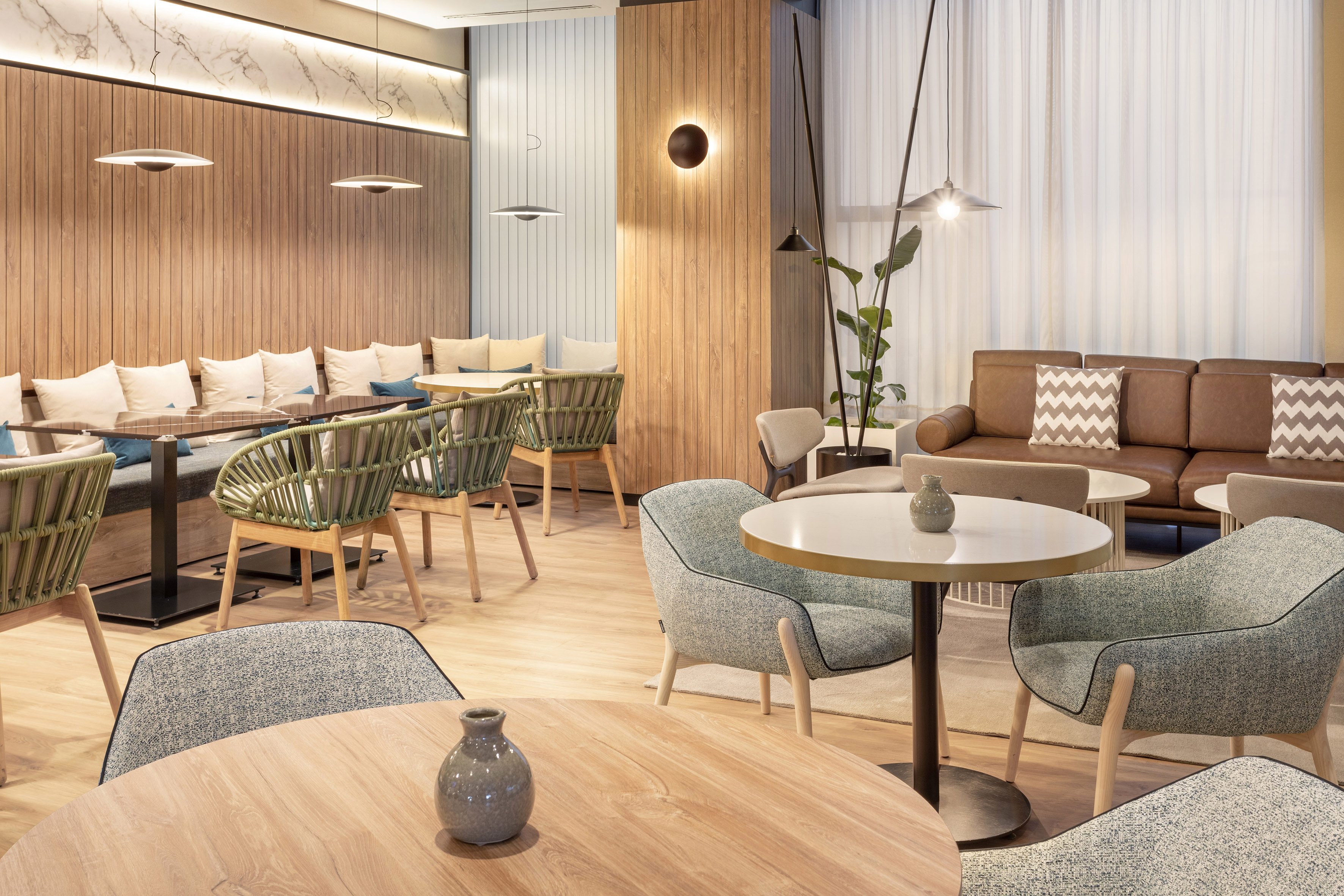 Modern lounge interior with diverse seating, wood panels, and soft ambient lighting.