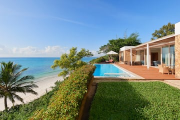 a pool and a house with a beach and trees