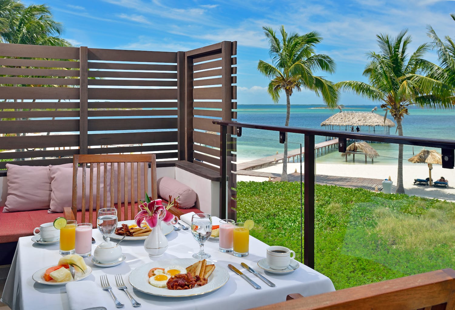 a table with food on it and a glass railing on a balcony overlooking the ocean