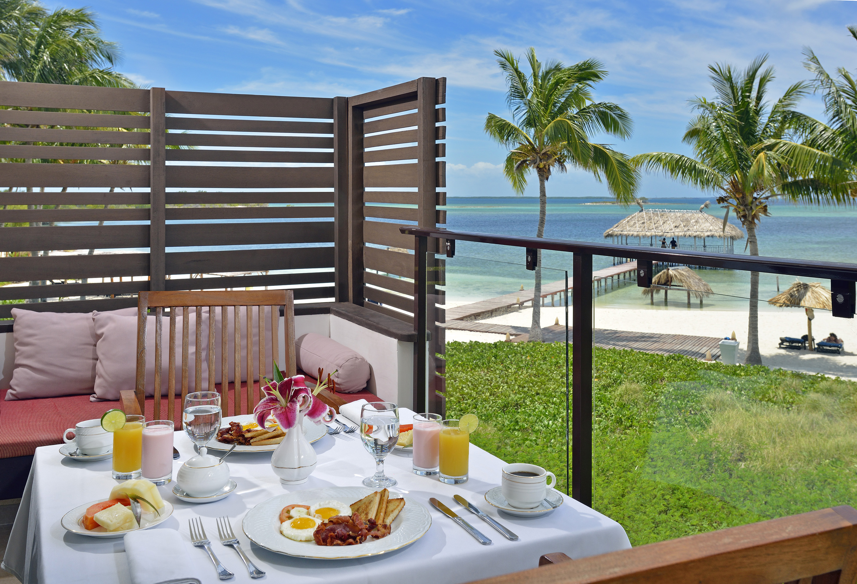 a table with food on it and a glass railing on a balcony overlooking the ocean