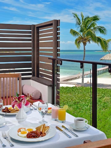 a table with food on it and a glass railing on a balcony overlooking the ocean