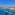 Rooftop glass pool overlooking a Mediterranean coastal town and distant island.