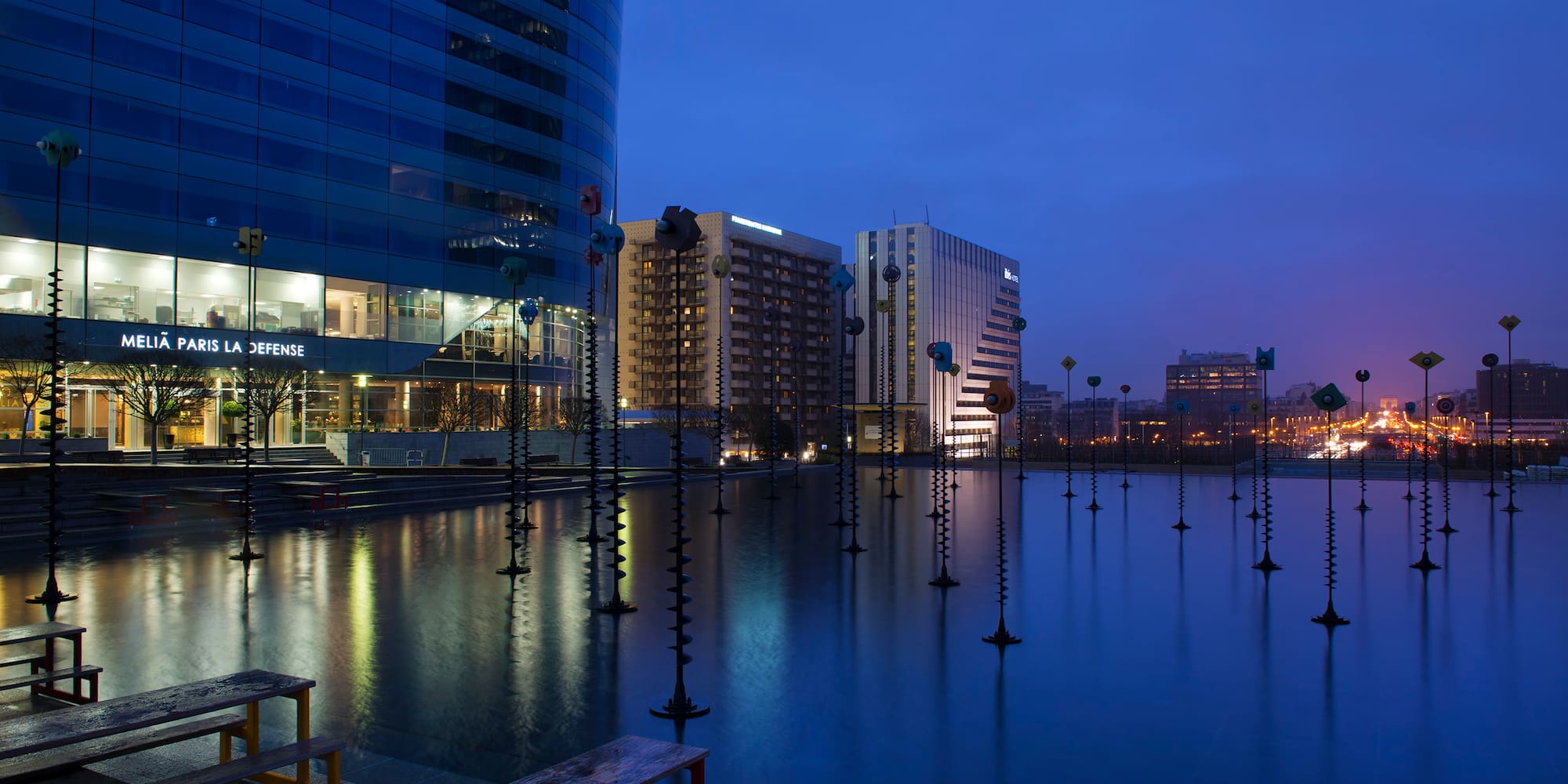 a water with poles in it and a building in the background