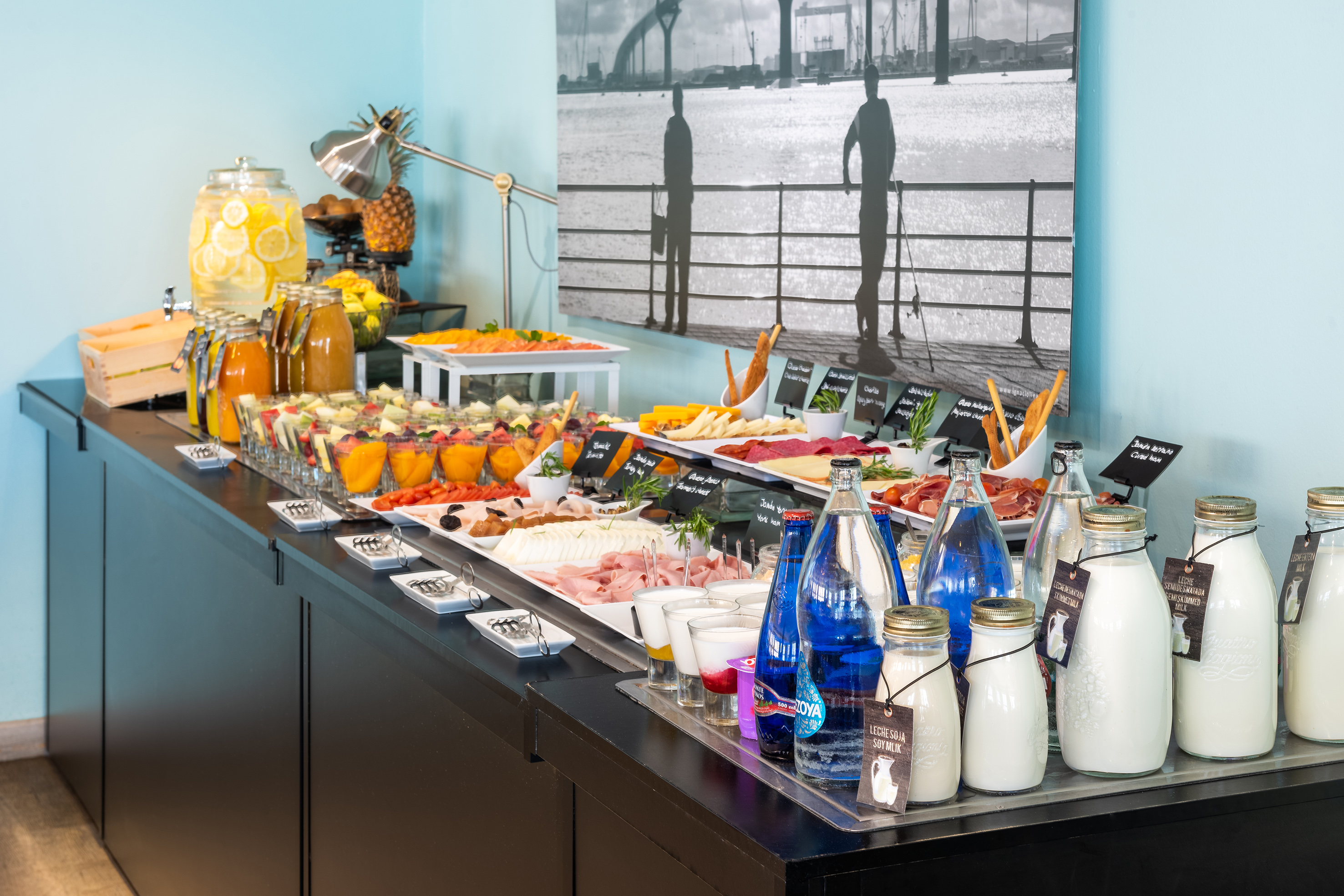 Fresh breakfast buffet with fruit, juices, cold cuts, cheeses, and milk.