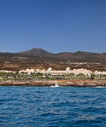 a body of water with buildings and mountains in the background