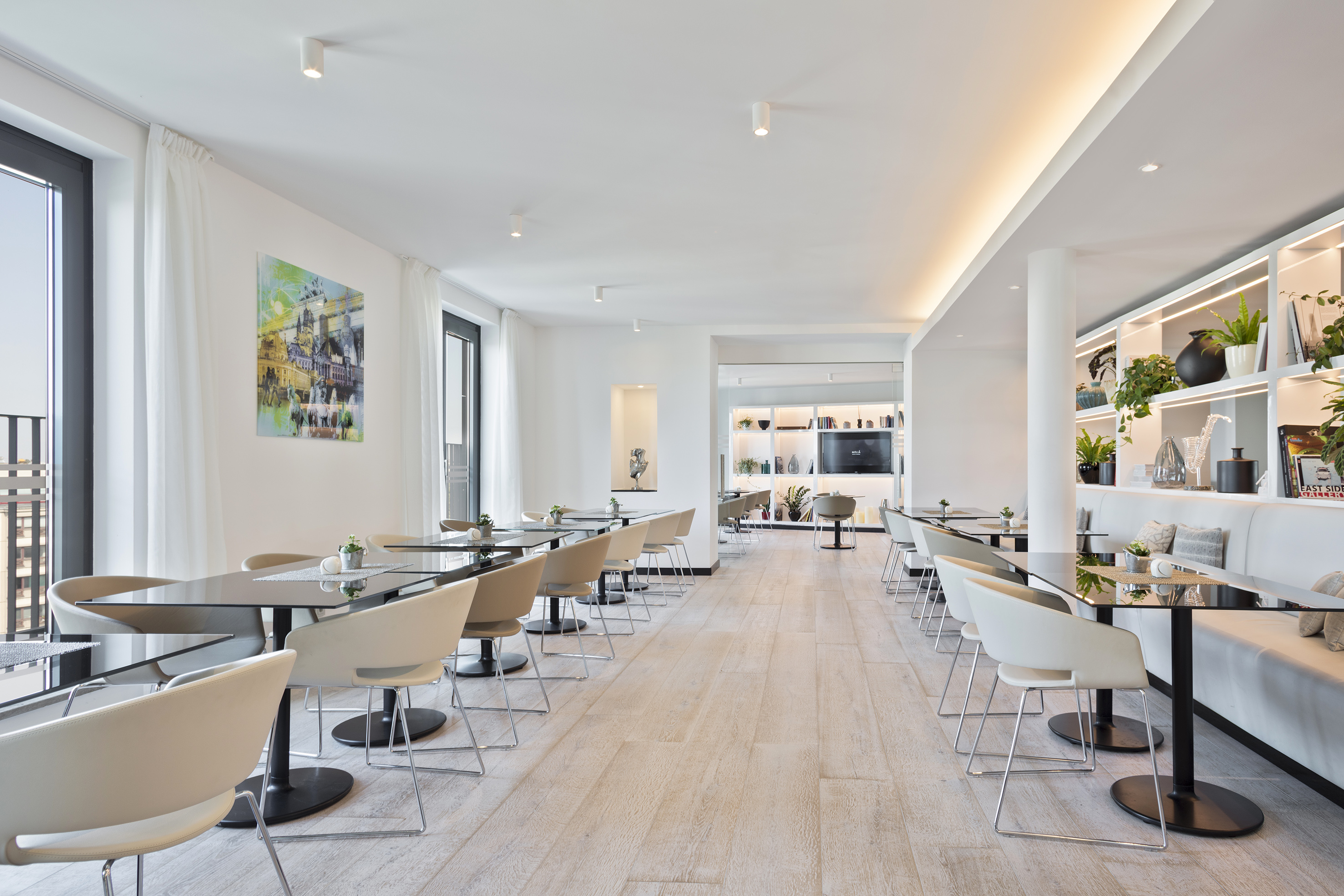Modern bright dining area with sleek tables, light chairs, and minimalist decor.
