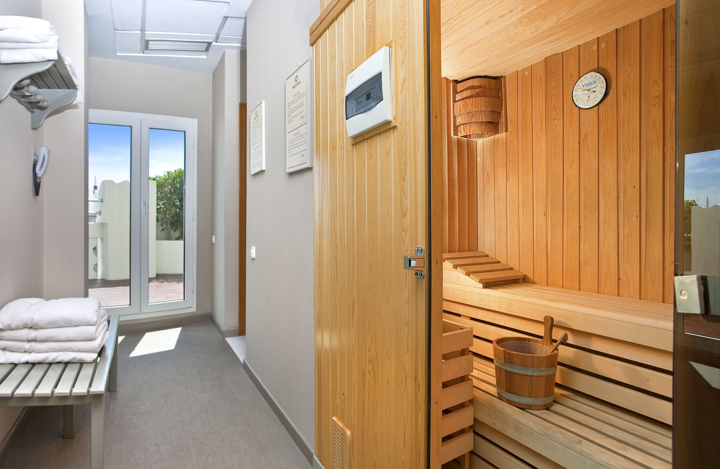 Modern wooden sauna and spa area with fresh towels and outdoor view.
