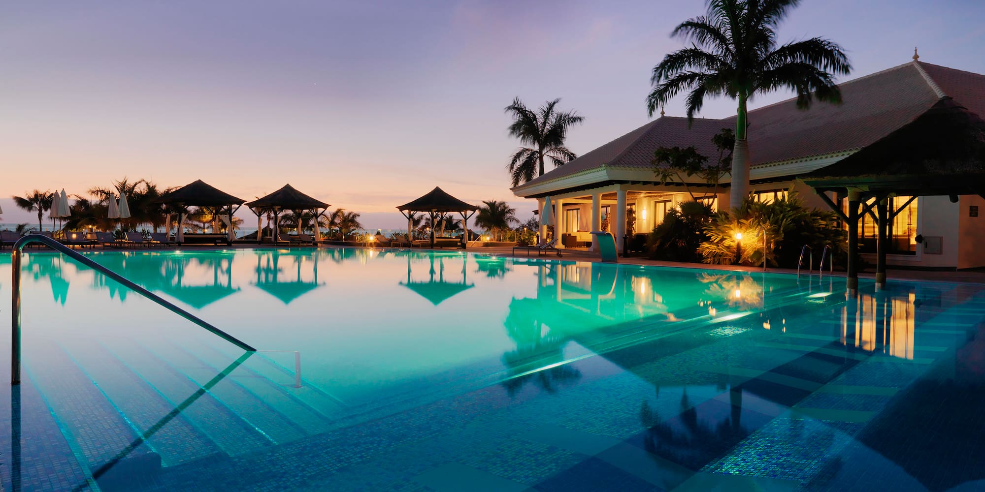 a pool with palm trees and a building