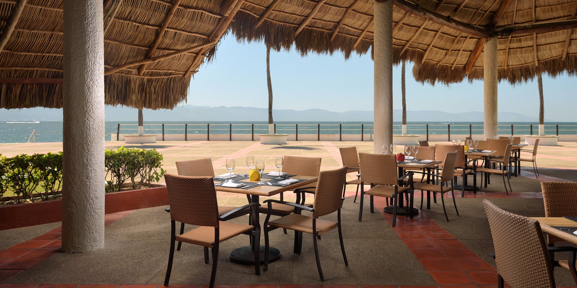 a table and chairs under a thatched roof