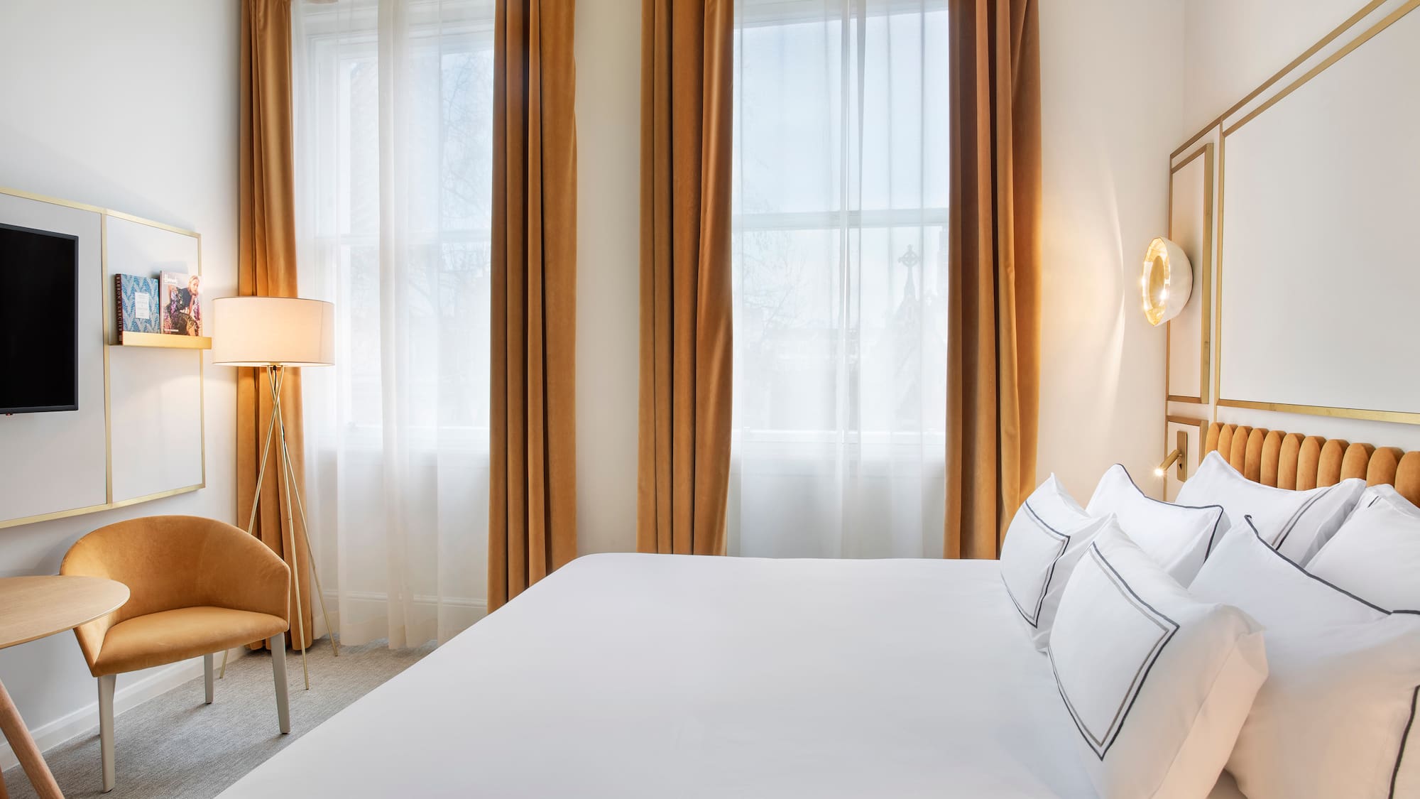 a bed with white sheets and a lamp in a room with curtains