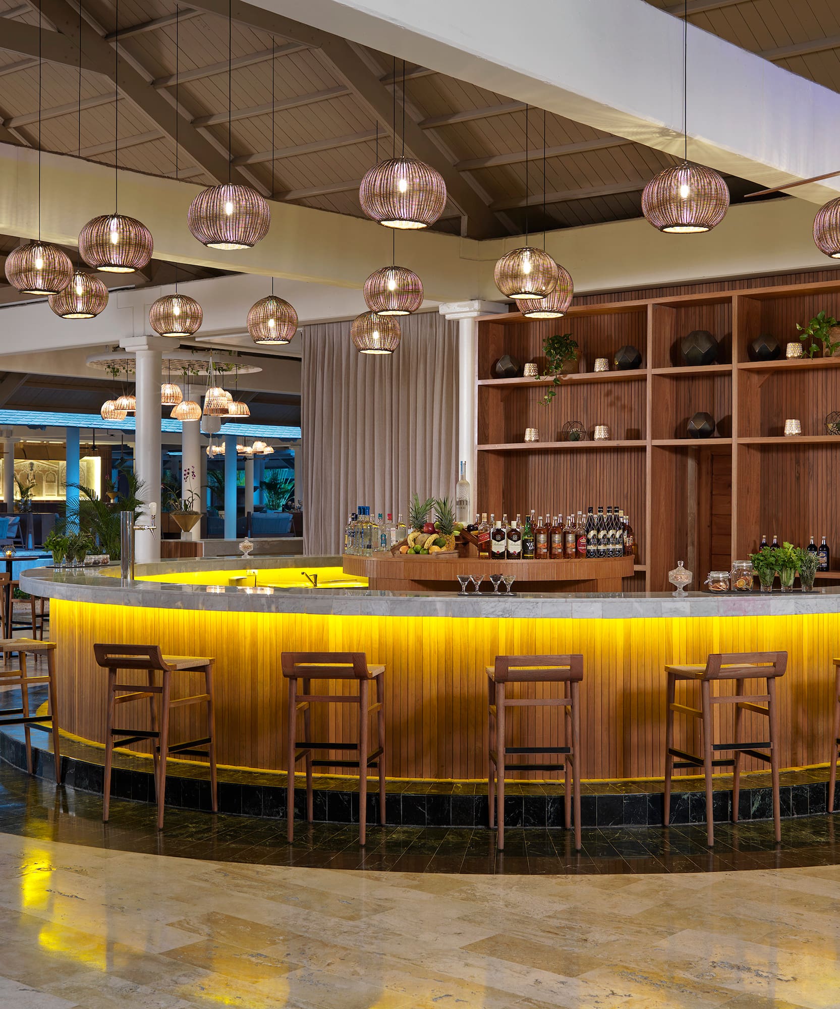 a bar with a counter and chairs in a room with lights from the ceiling