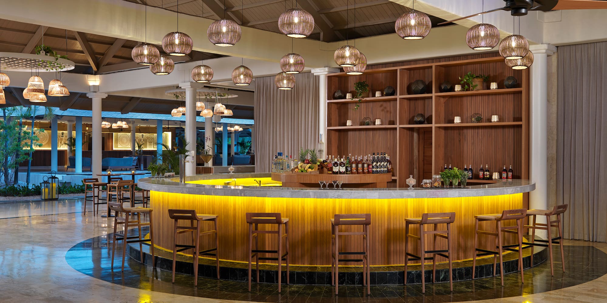 a bar with a counter and chairs in a room with lights from the ceiling