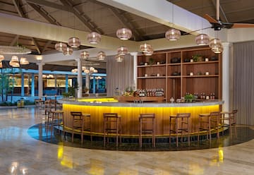a bar with a counter and chairs in a room with lights from the ceiling