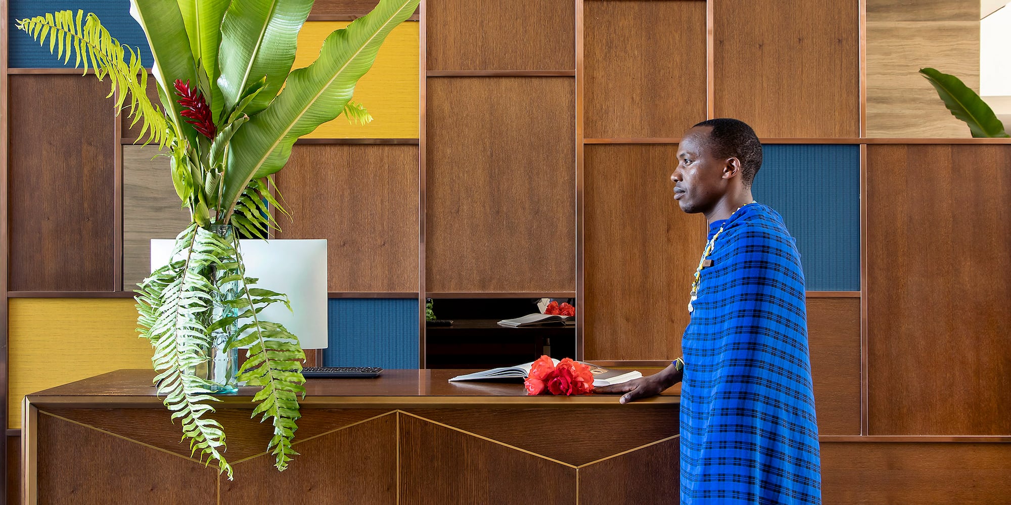 a man standing at a desk in a room with a plant