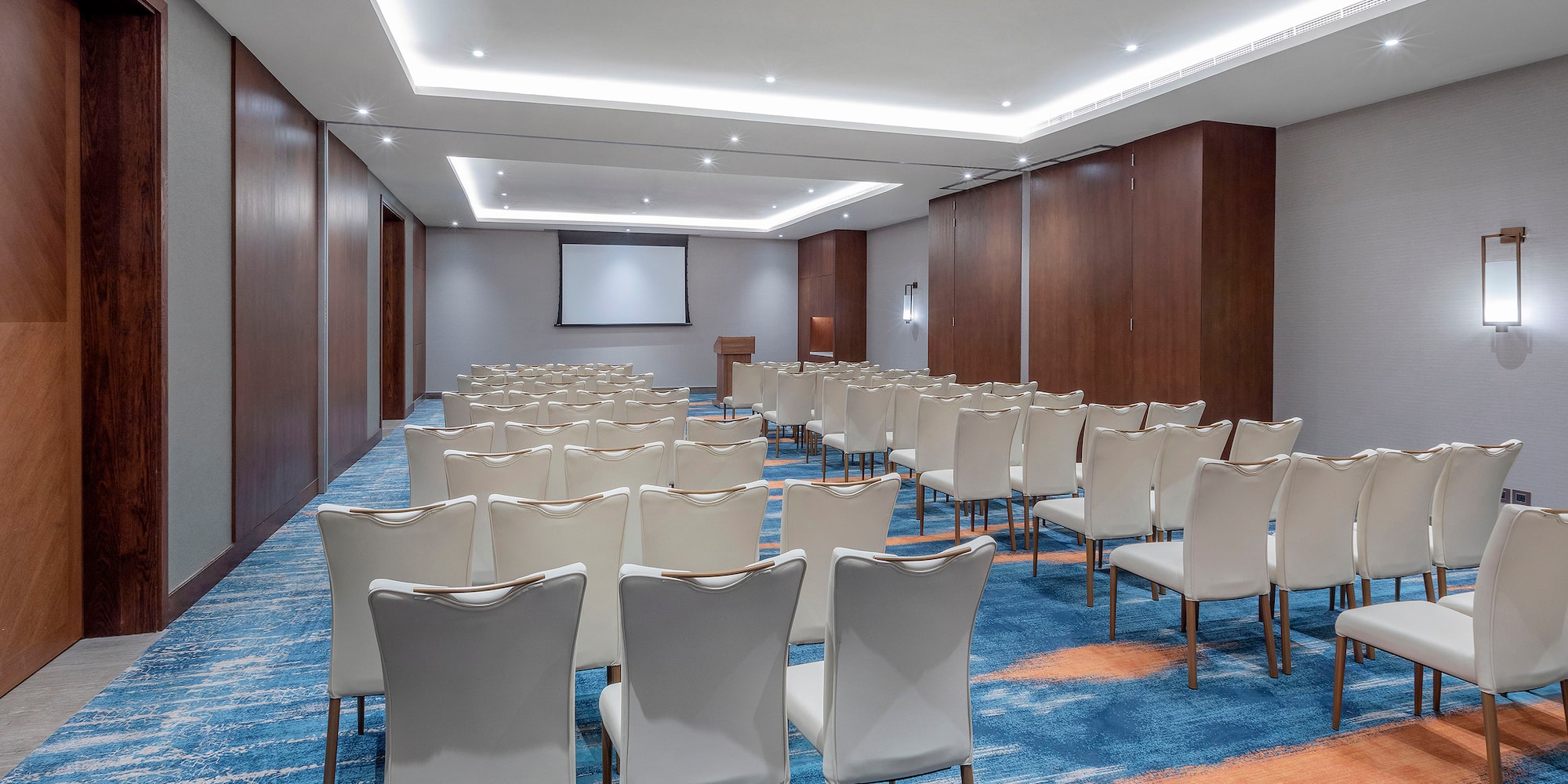 a room with white chairs and a projector screen