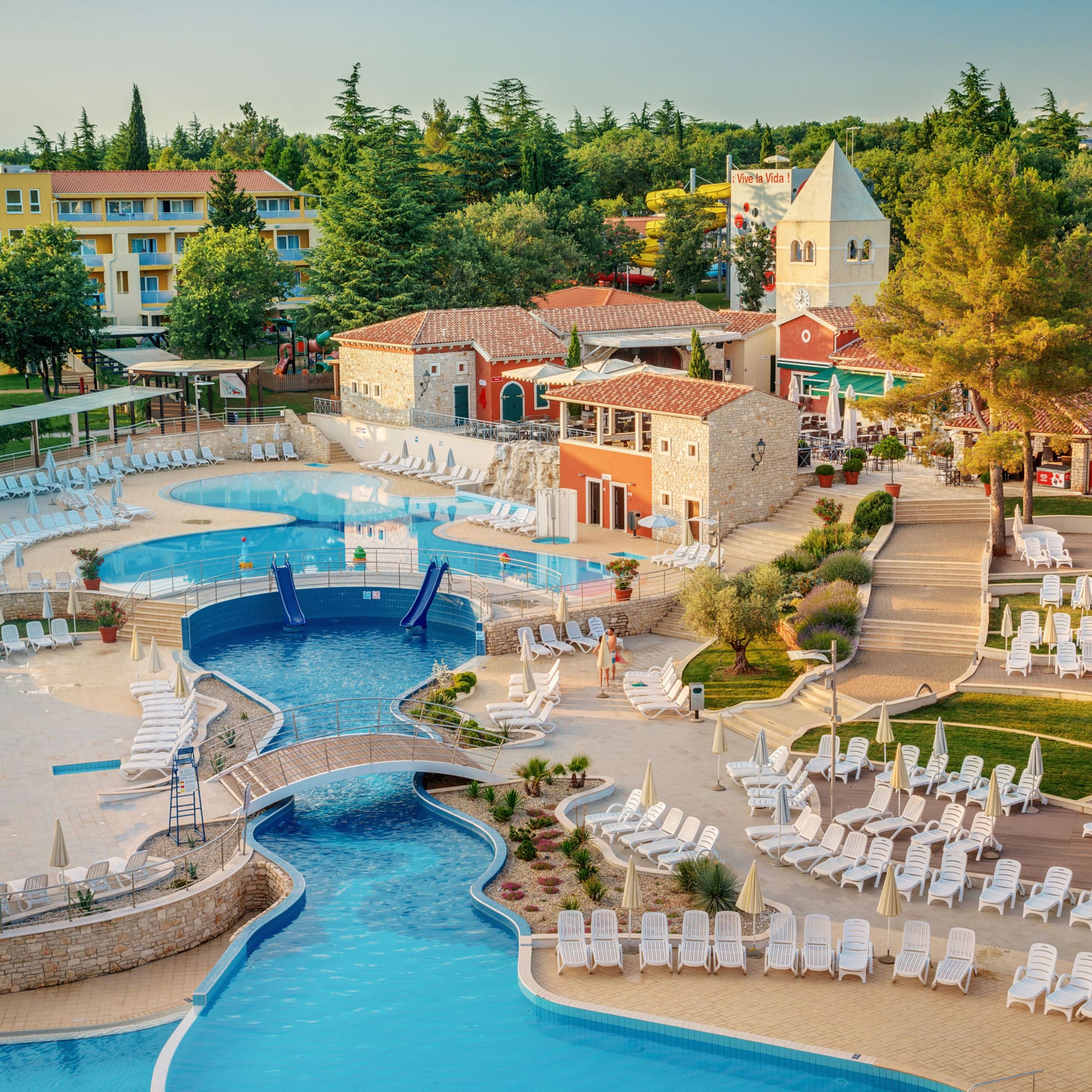 a swimming pool with chairs and a bridge