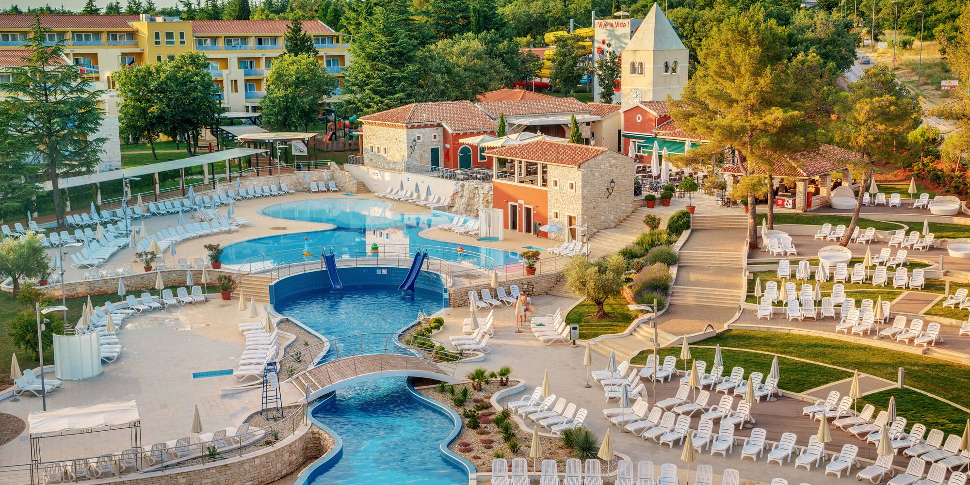 a swimming pool with chairs and a bridge