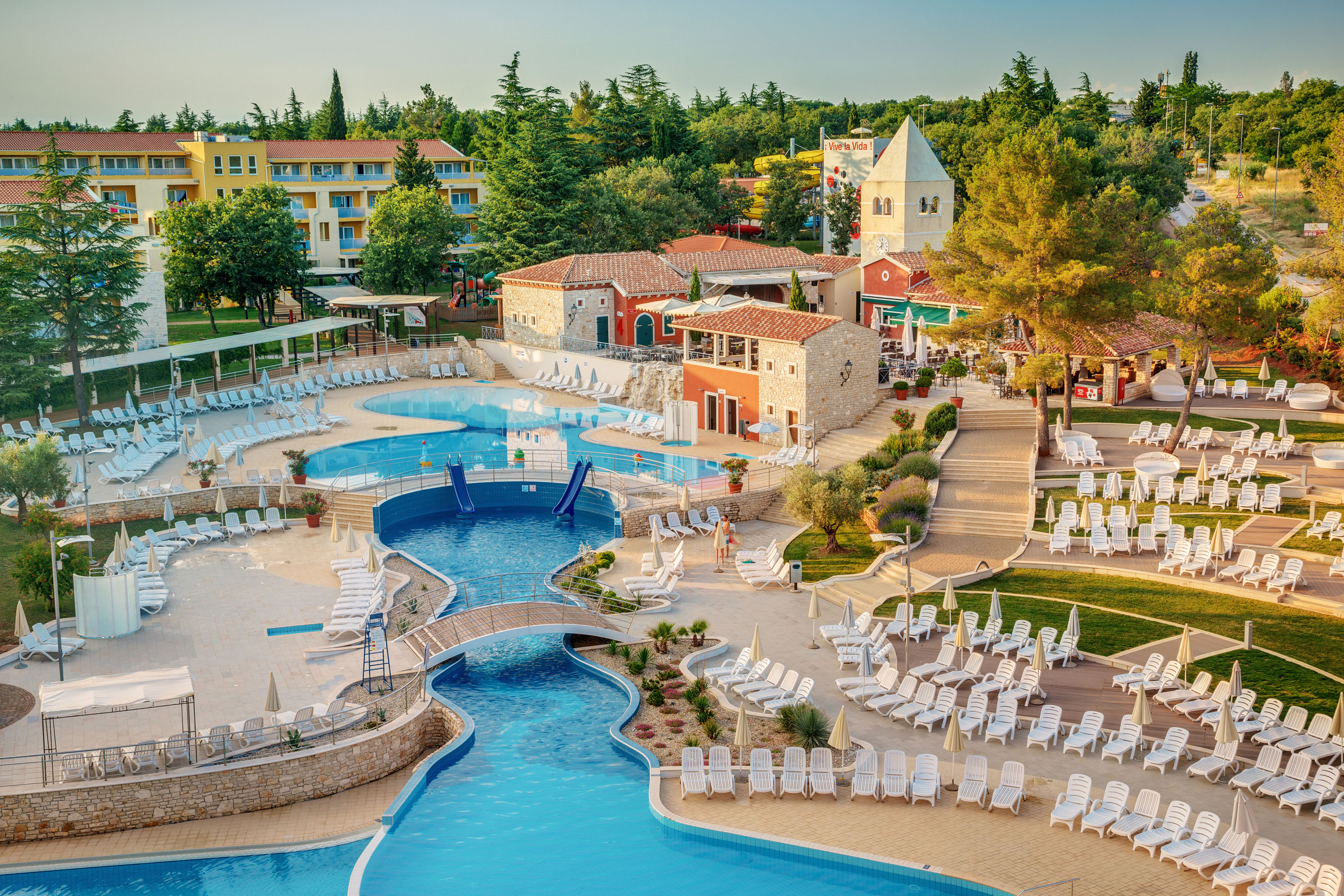 a swimming pool with chairs and a bridge