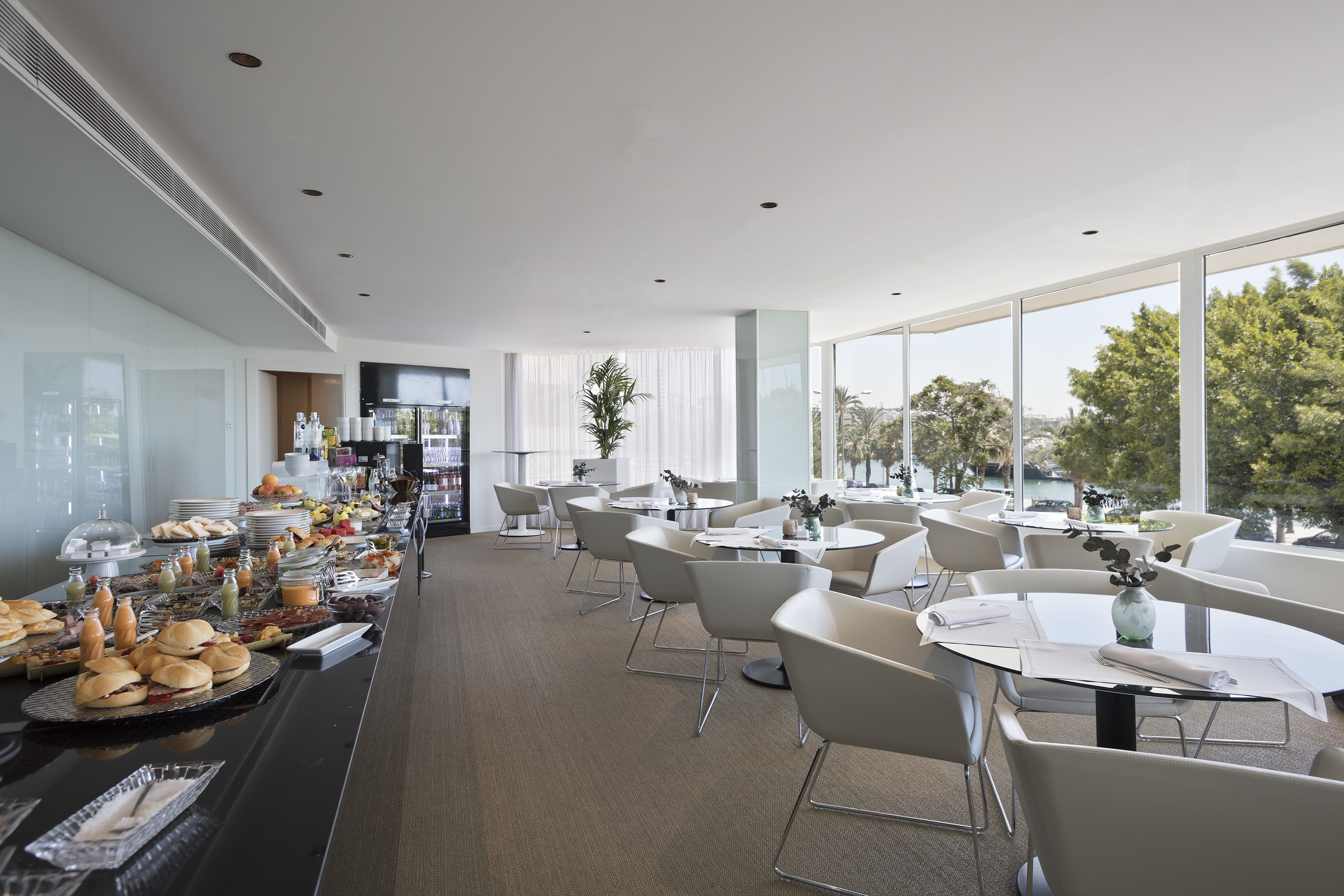 Modern hotel breakfast buffet with waterfront view and bright dining area.