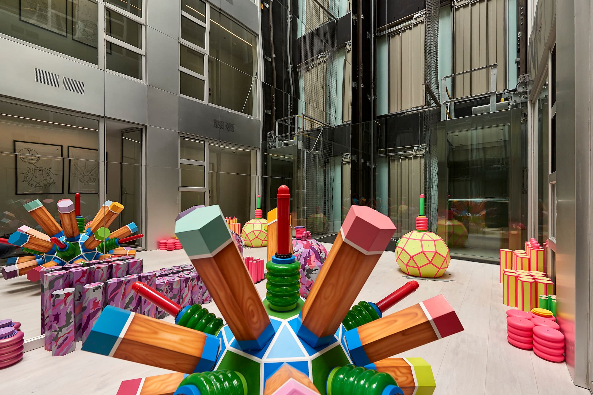 Colorful oversized pencil sculptures art installation in modern building atrium.