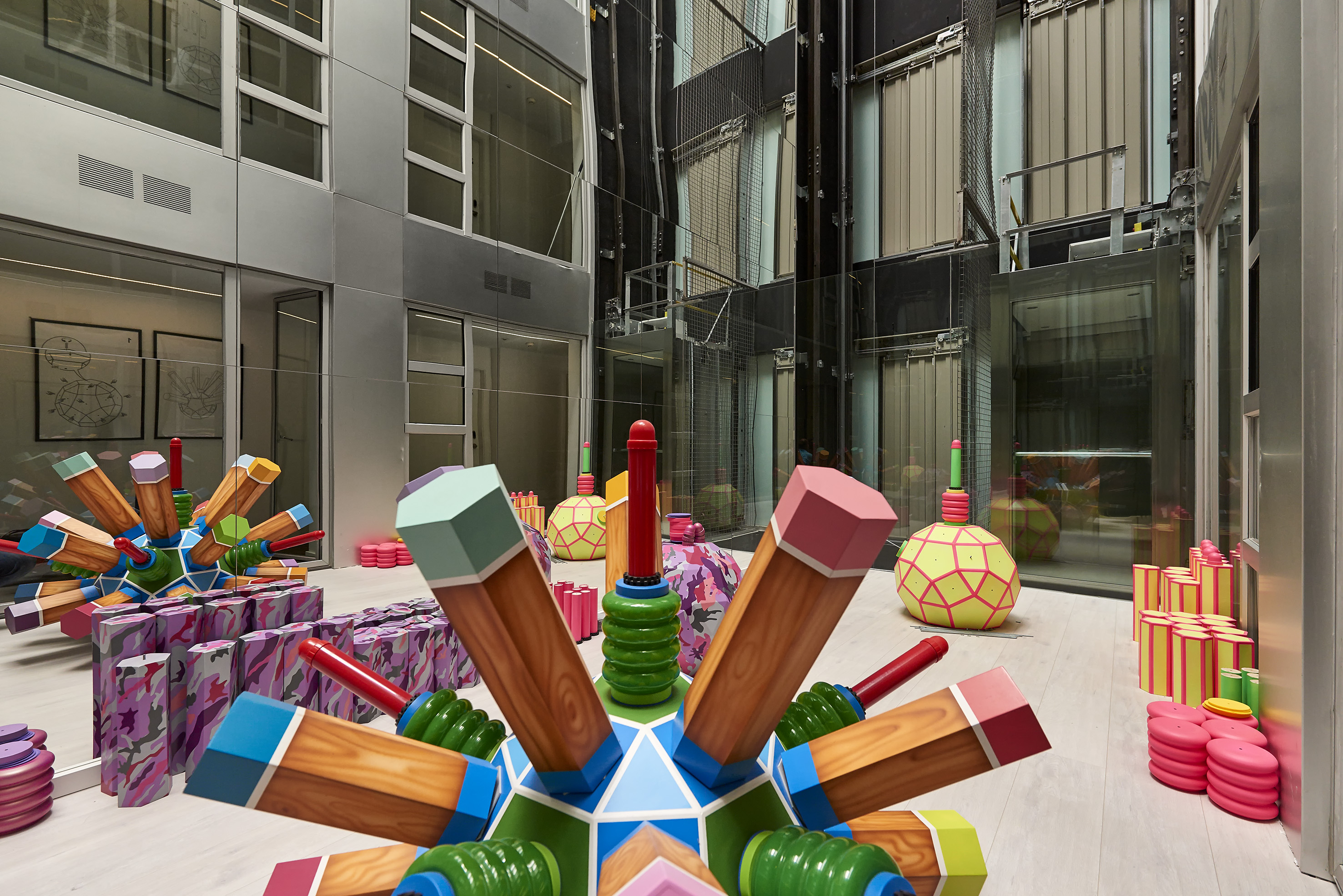 Colorful oversized pencil sculptures art installation in modern building atrium.