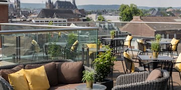 a patio with chairs and tables and plants on a rooftop