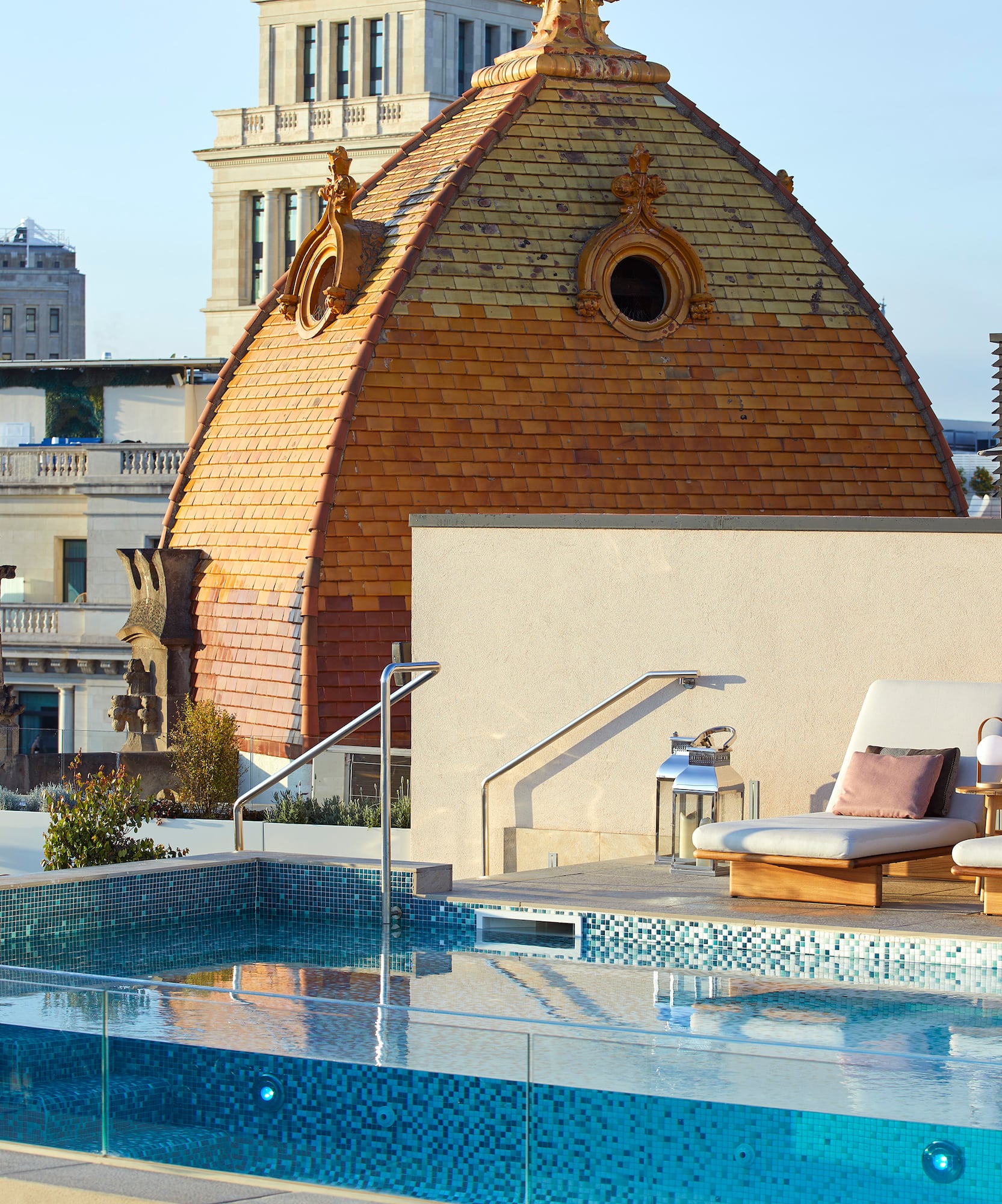 Sunny rooftop infinity pool with lounge chairs and historic domed building.