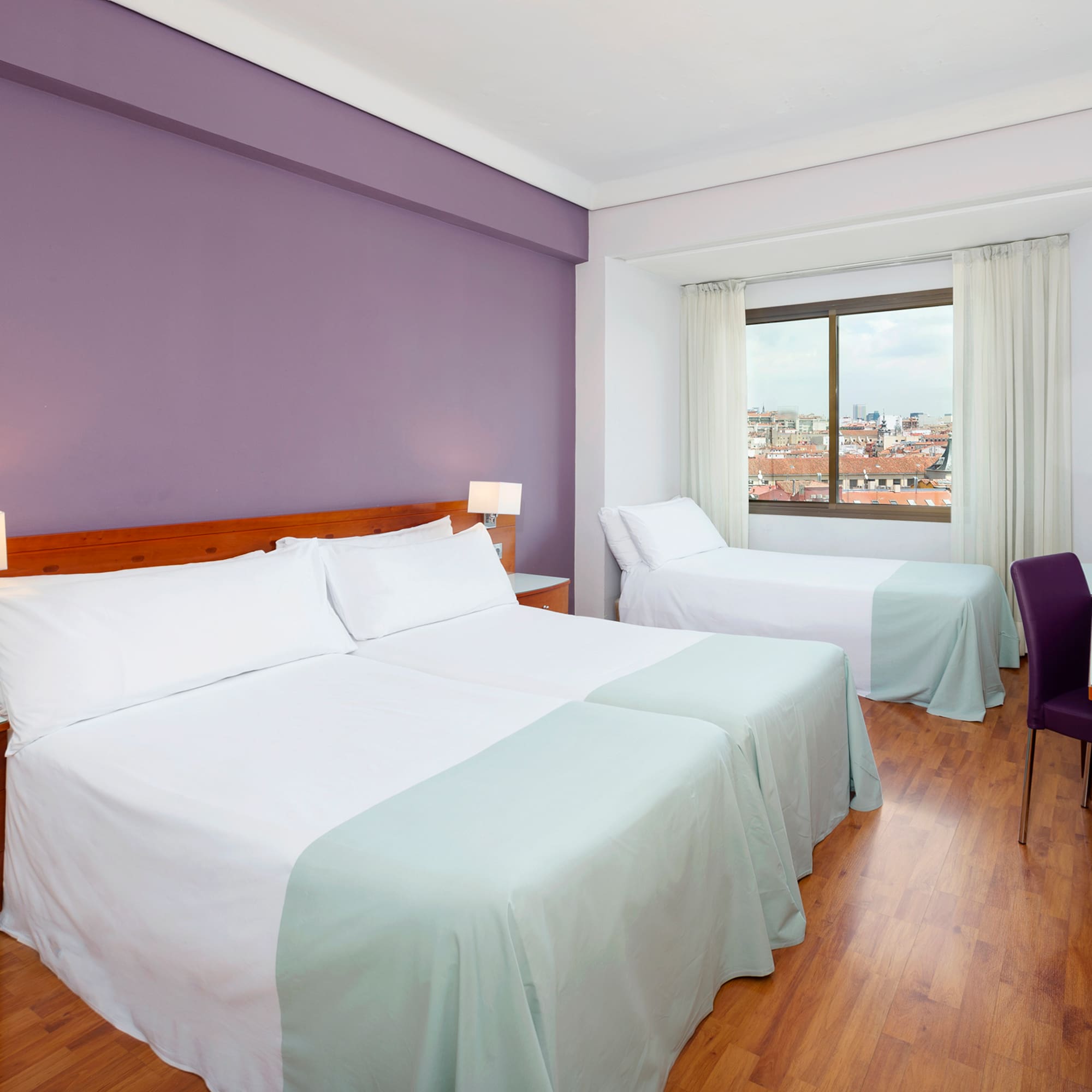 a room with two beds and a purple wall