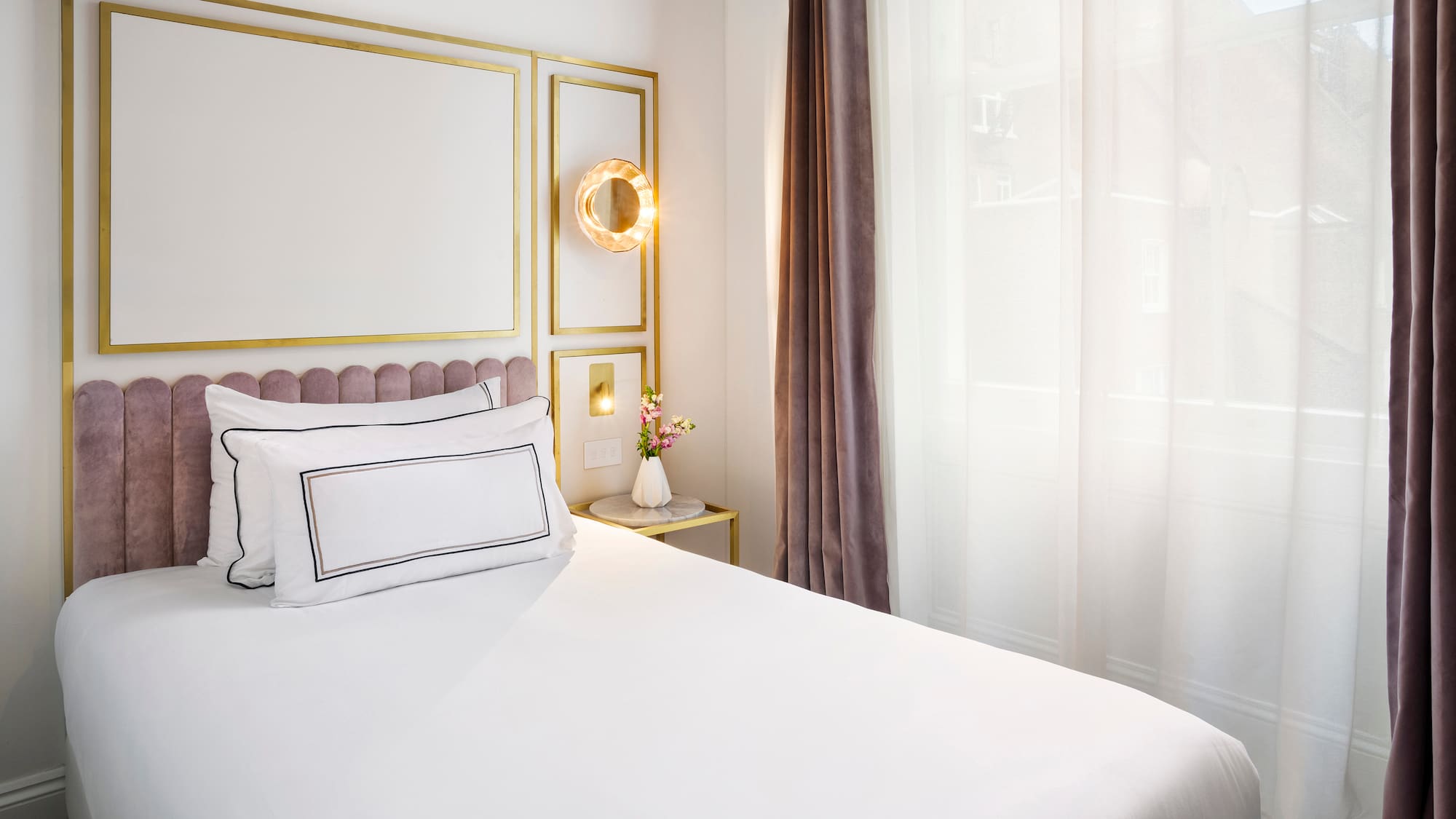 a bed with white sheets and pillows in a room with curtains