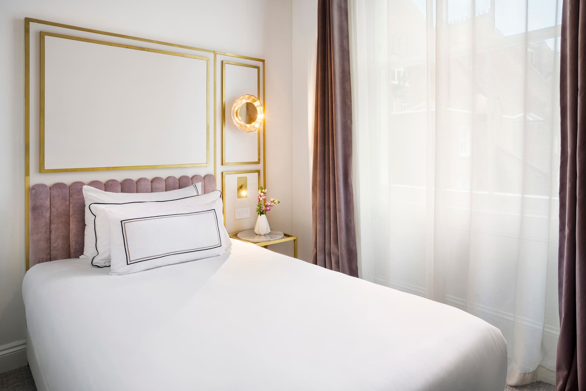 a bed with white sheets and pillows in a room with curtains