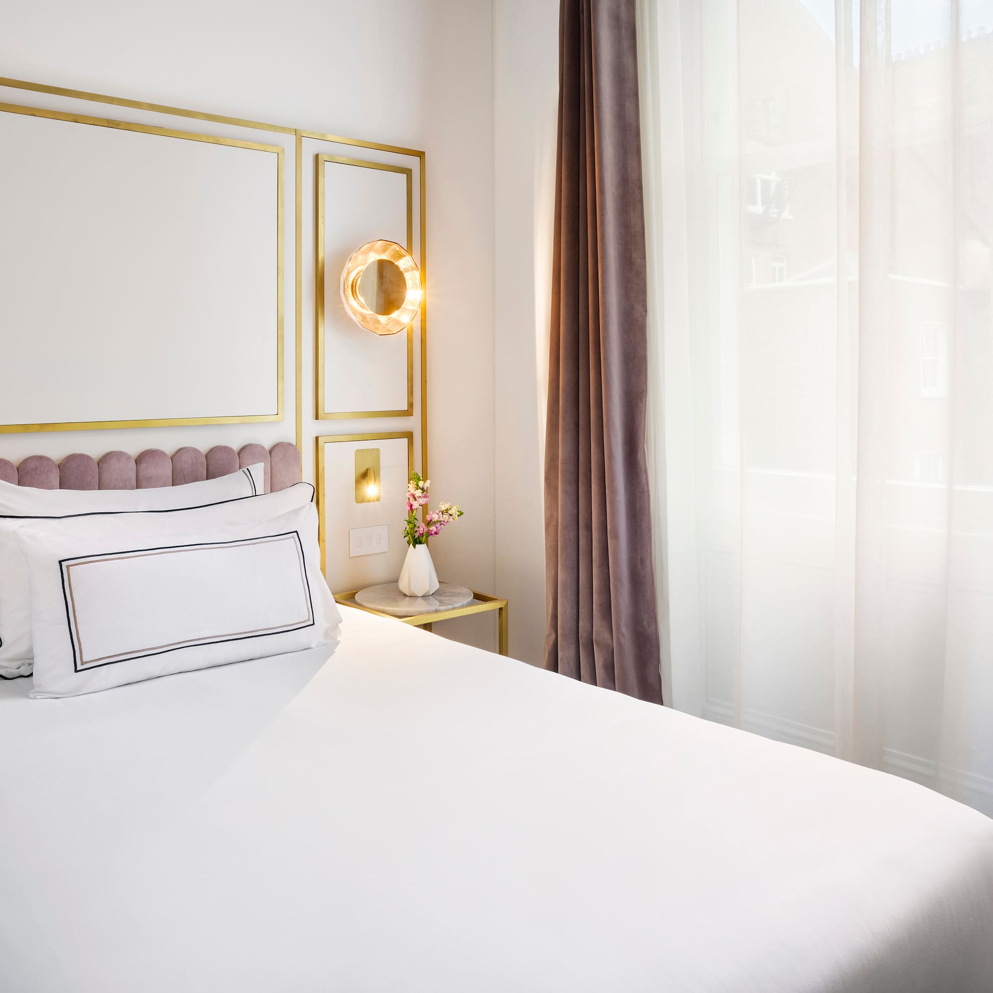 a bed with white sheets and pillows in a room with curtains