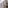 Modern stone facade building, large reflective windows, blurred olive tree.