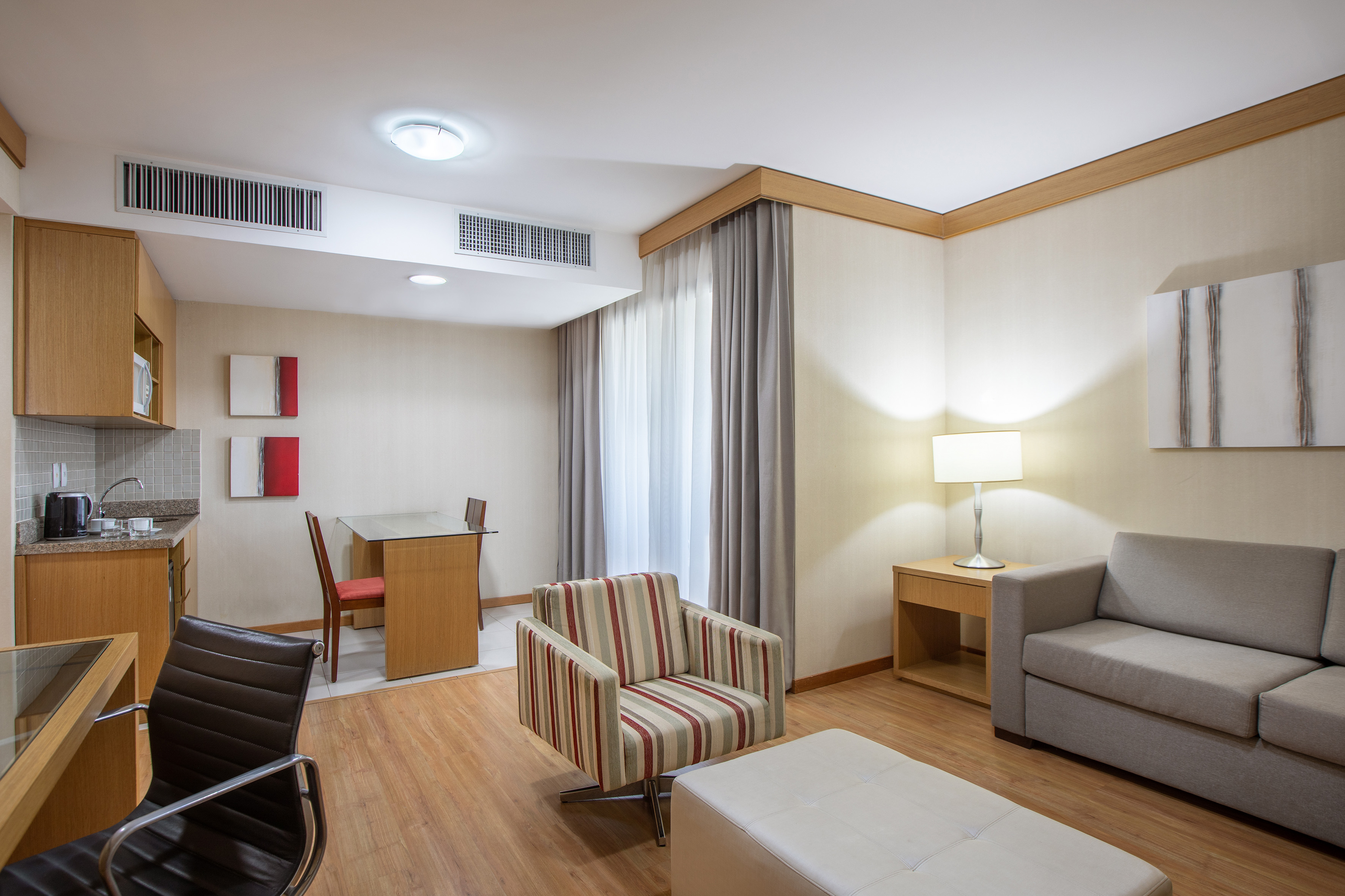 Modern hotel suite with kitchenette, living area, and dining space.