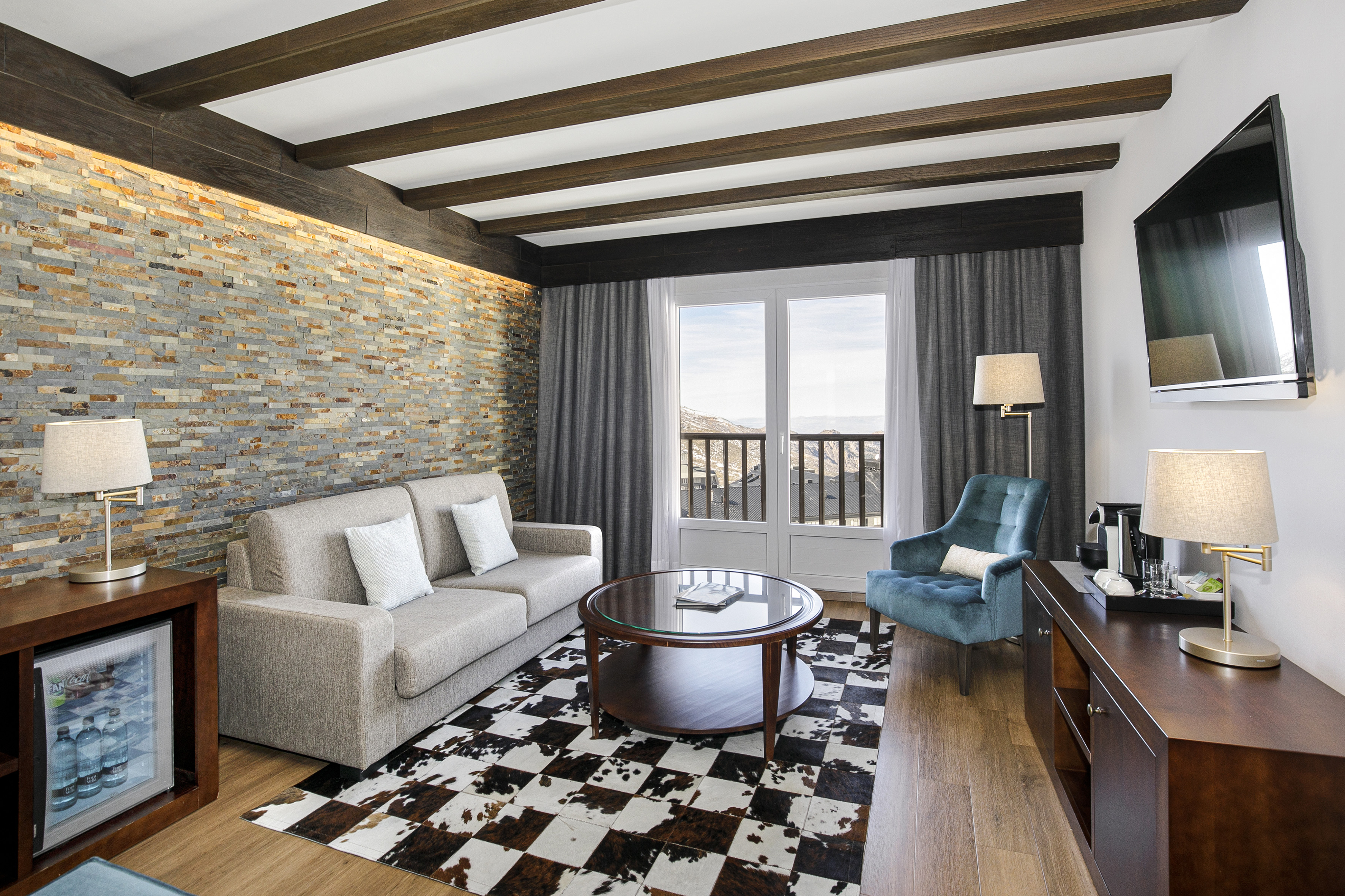 Luxury hotel living room with stone wall, cowhide rug, and mountain resort view.