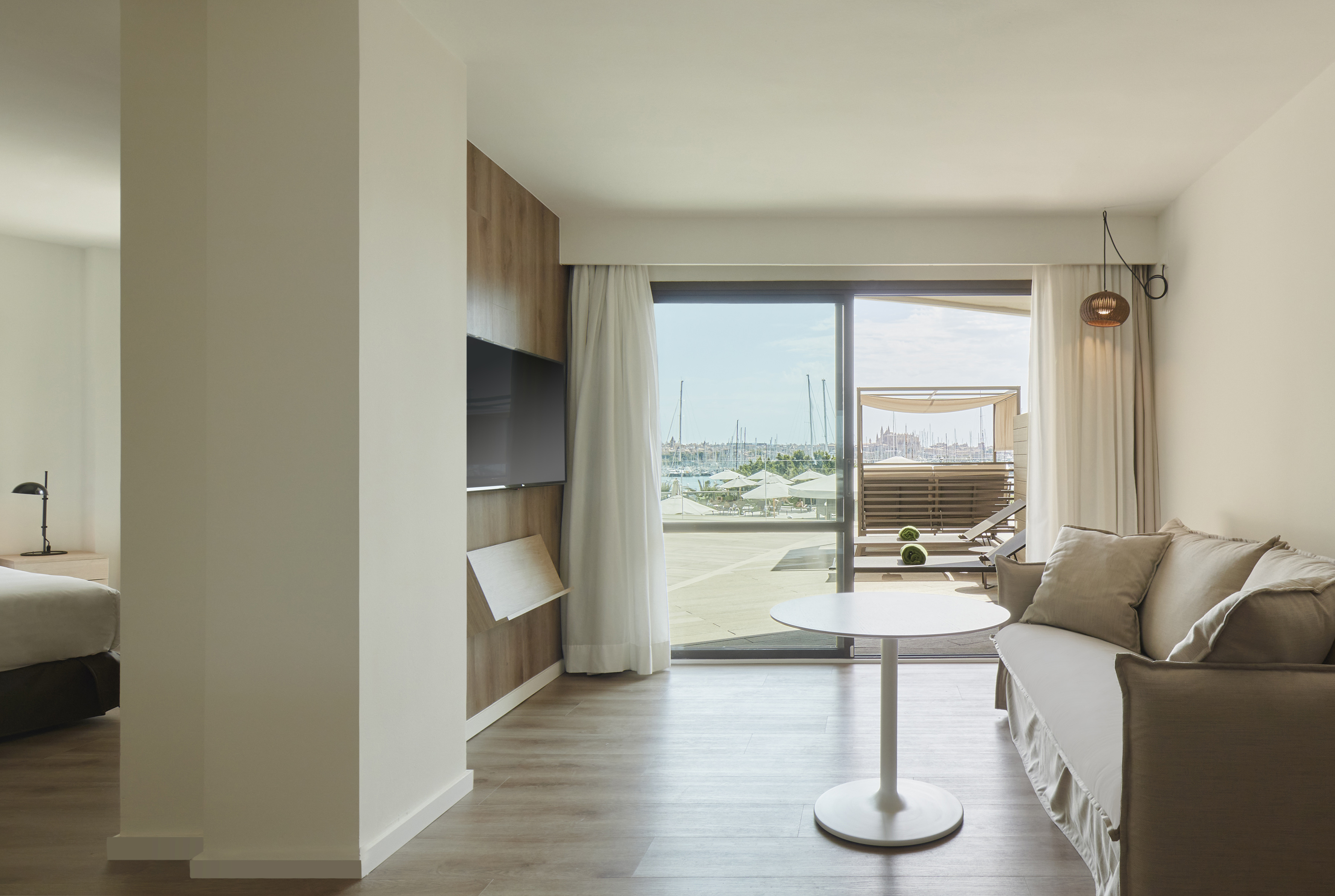 Luxury hotel suite with balcony overlooking a vibrant marina and Palma city.