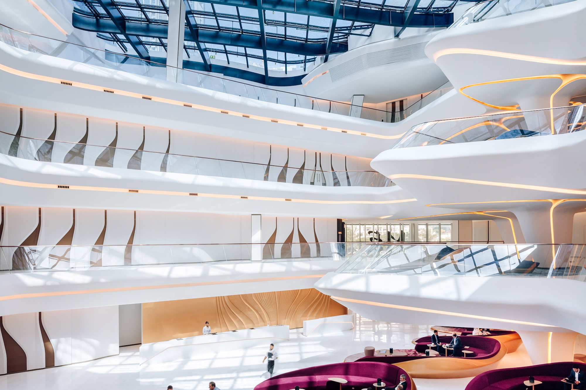 Luxury modern lobby, curved white architecture, glass skylight, purple lounge.