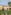 Grand Italian building exterior with palm trees and lush circular garden.