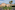 Peach Mediterranean building, lush garden, two tall palm trees, cobblestone path.