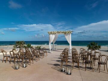 a wedding ceremony set up with chairs and a beach in the background