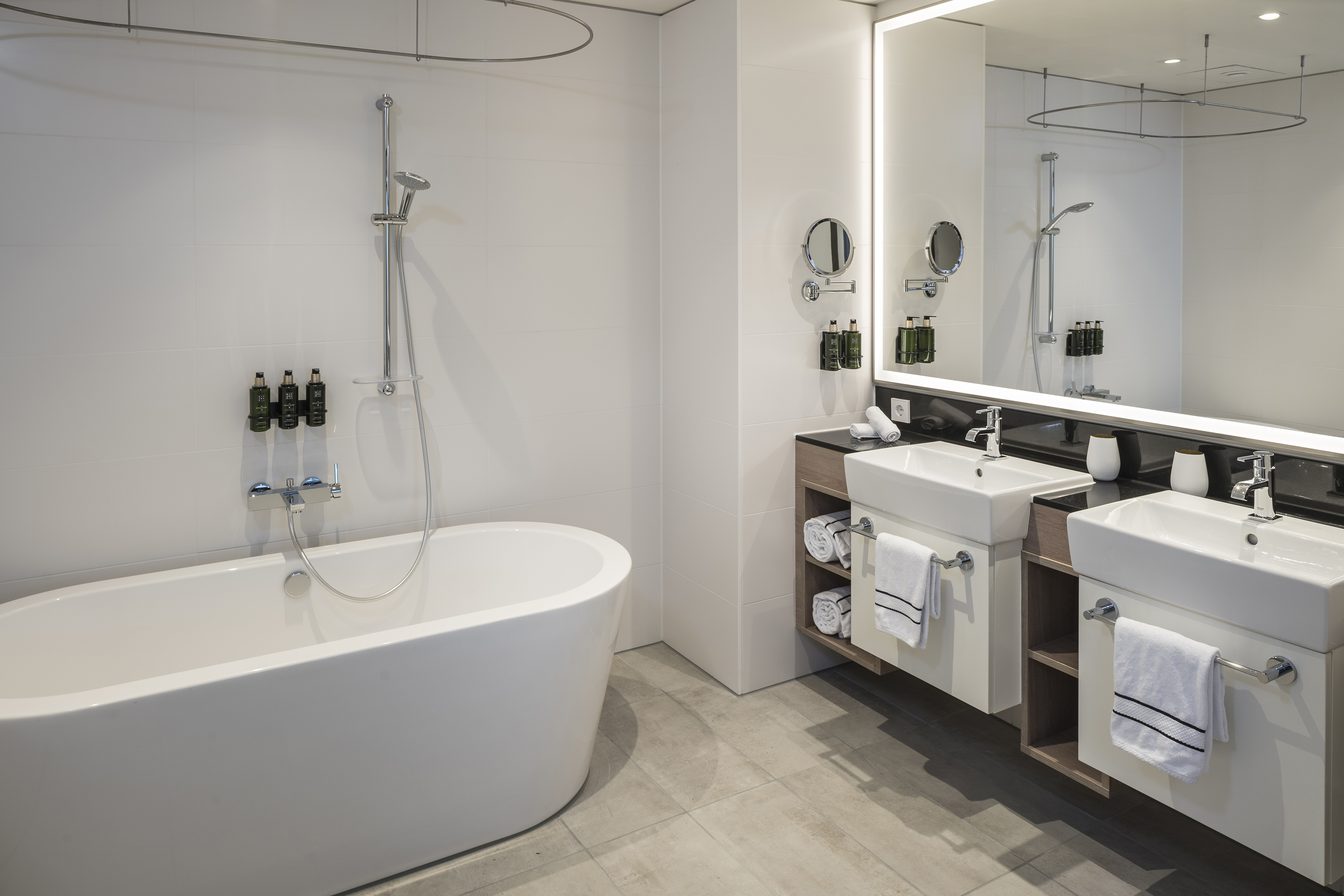 Modern hotel bathroom with freestanding tub, shower, and double vanity sinks.