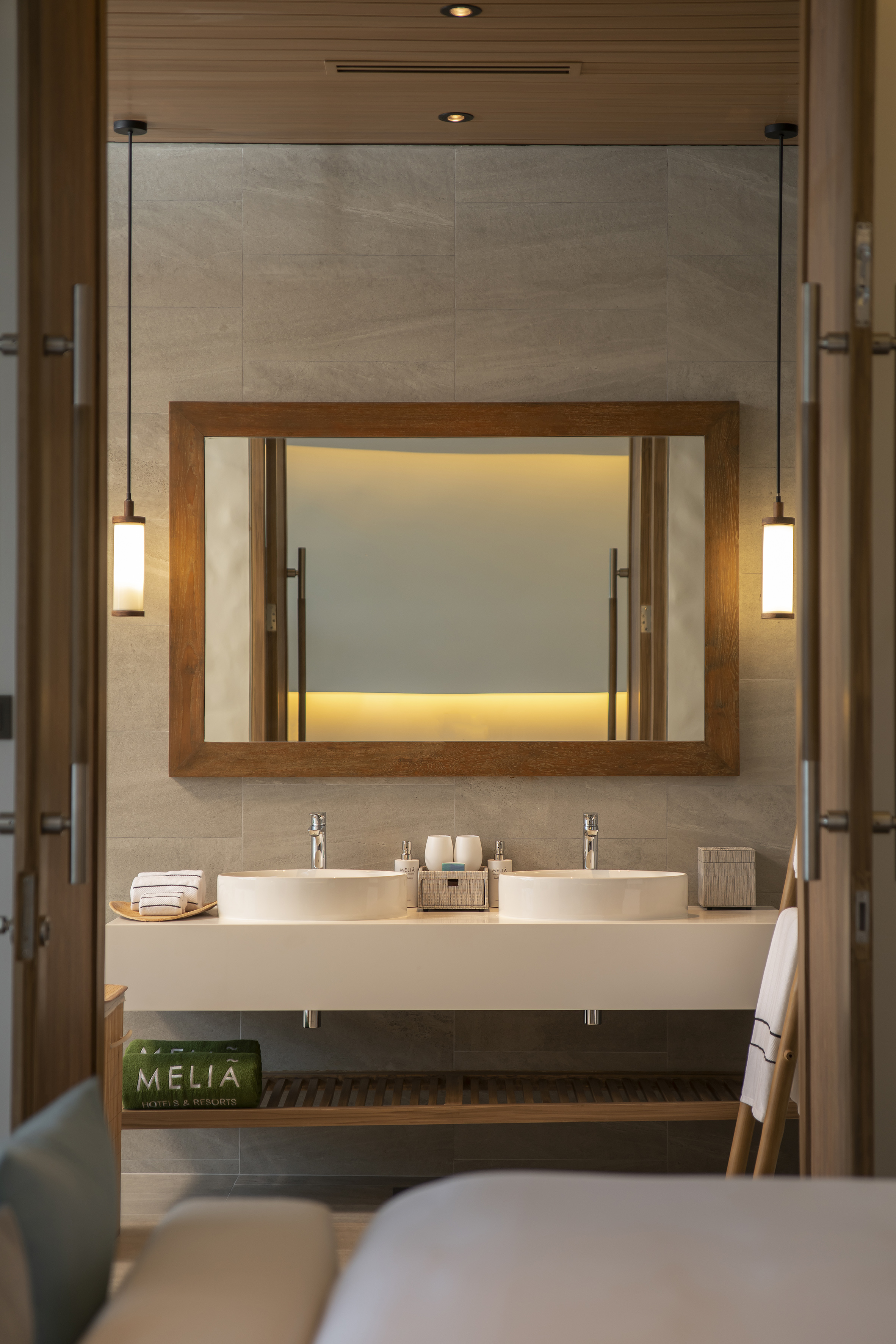 Meliá hotel bathroom with double vanity, illuminated mirror, and pendant lights.