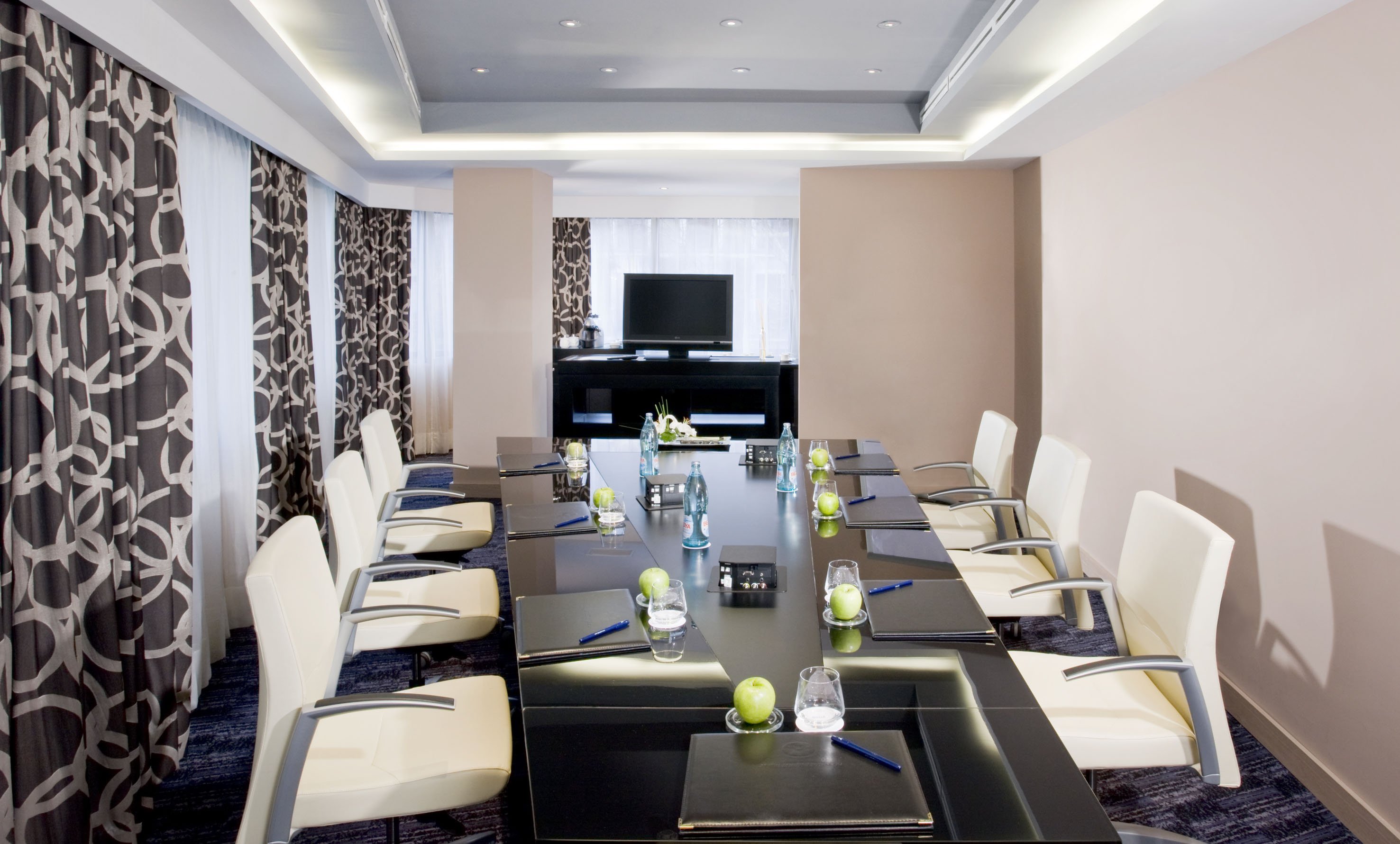 Professional conference room with black table, white chairs, and TV screen.