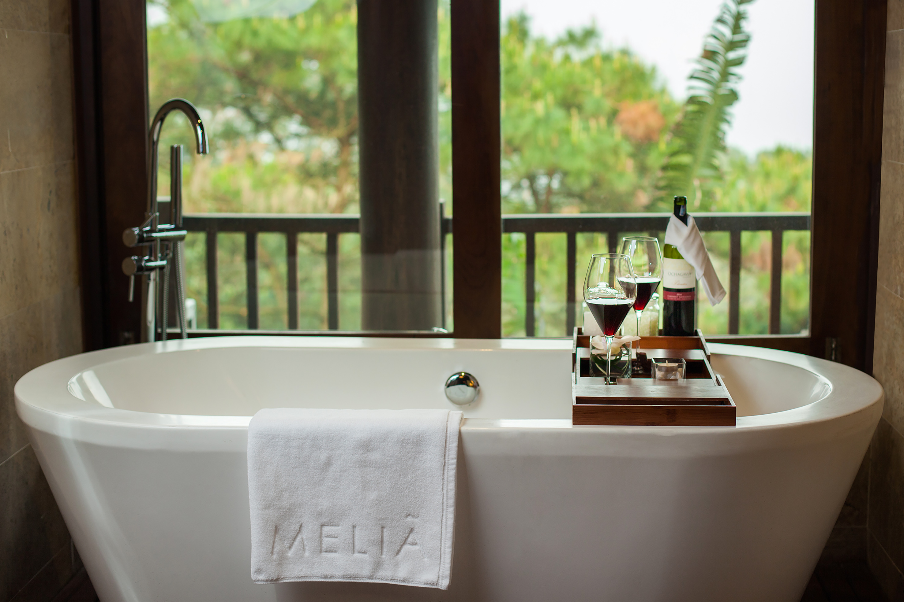 a bathtub with wine glasses and a tray on it