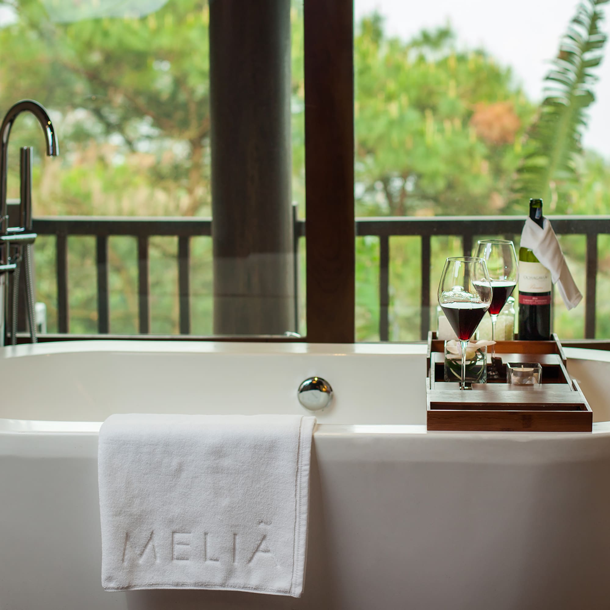 a bathtub with wine glasses and a tray on it
