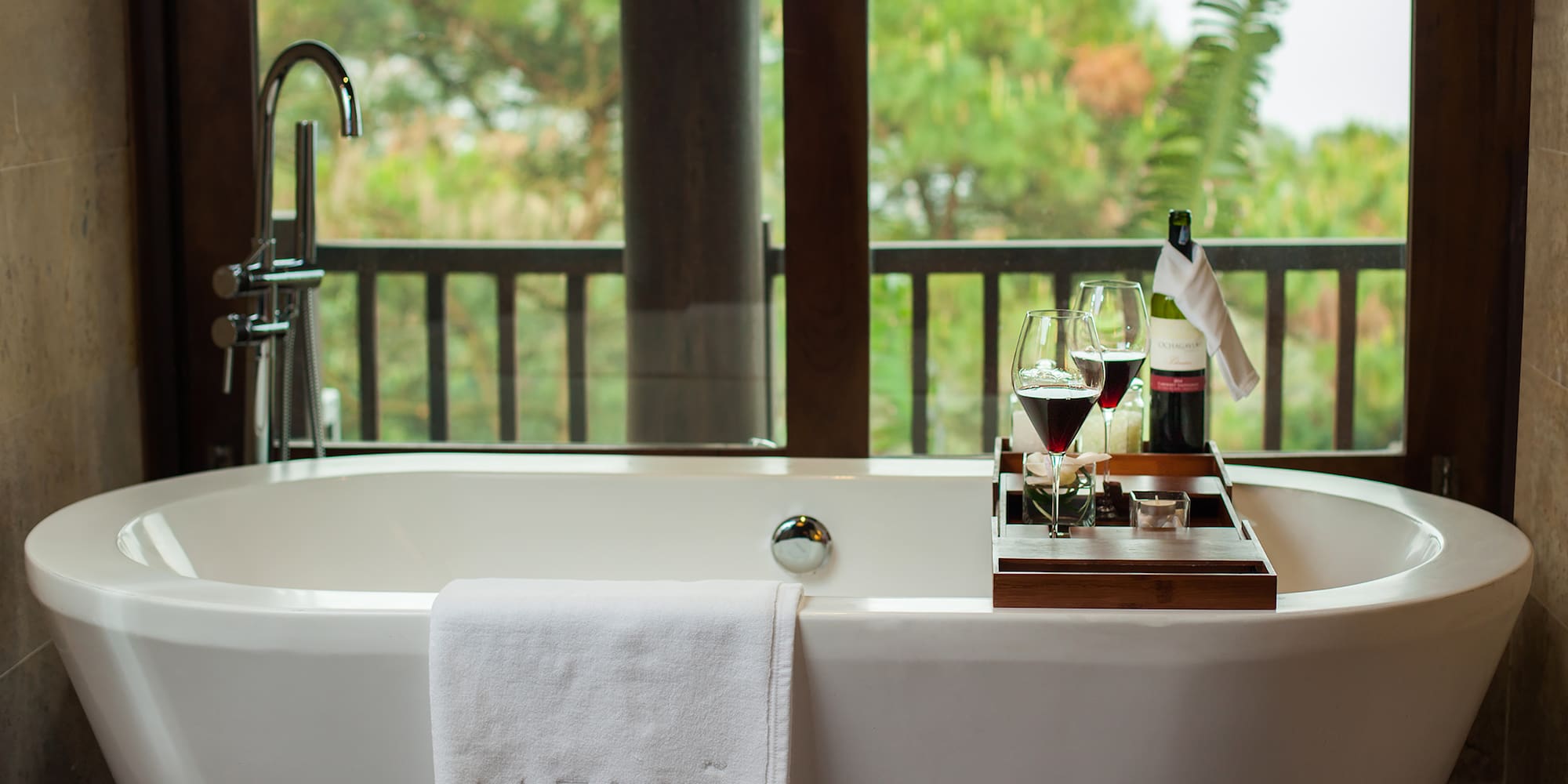 a bathtub with wine glasses and a tray on it